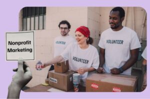 Hand hält Schild welches sagt Nonprofit Marketing. Im Hintergrund ist eine Gruppe Volunteers etwas am verteilen.